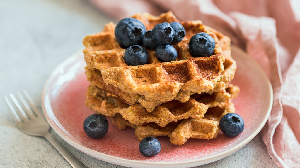 A batch of healthy gluten-free banana oat waffles topped with blueberries