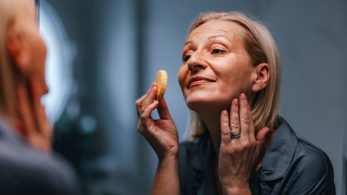 Close up shot of a beautiful senior woman applying make up with a sponge as a part of her morning beauty routine.