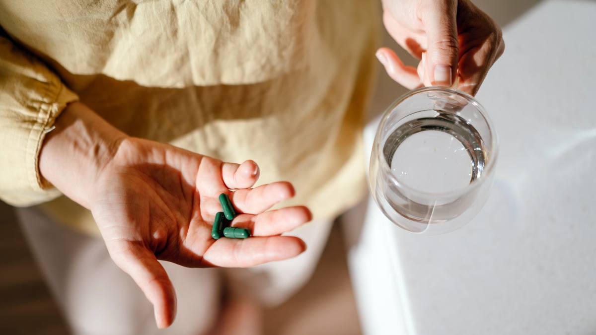 Woman holding green capsules