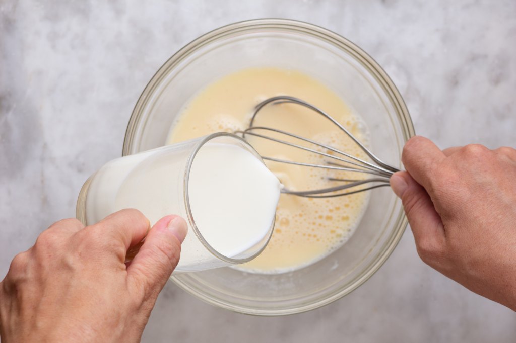 woman adding milk to ice cream pancakes batter