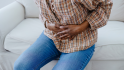 woman holding abdomen in pain, which is one of the symptoms of ovarian cancer