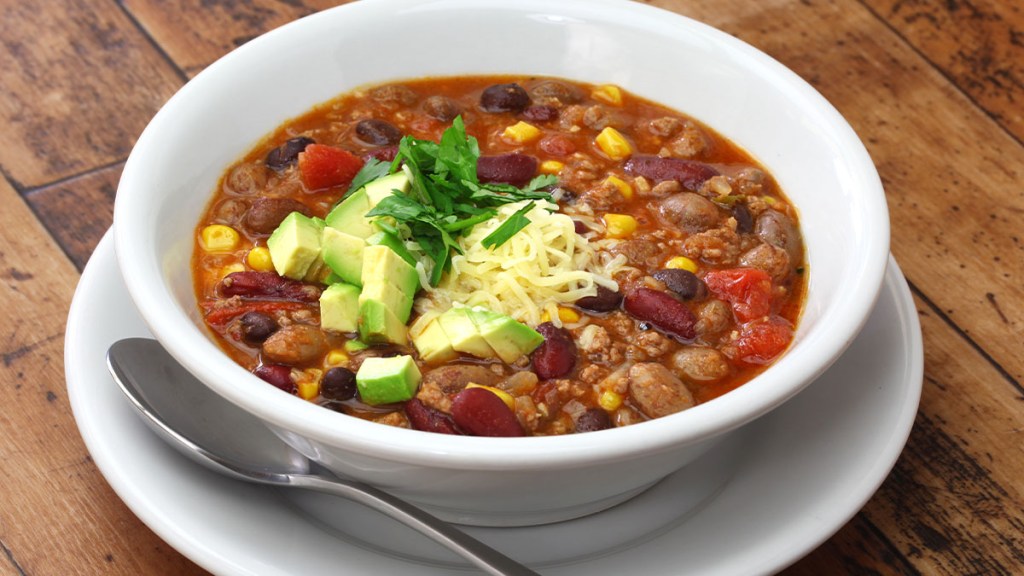 Bowl of "Superhero Soup" with beans and tomatoes topped with avocado