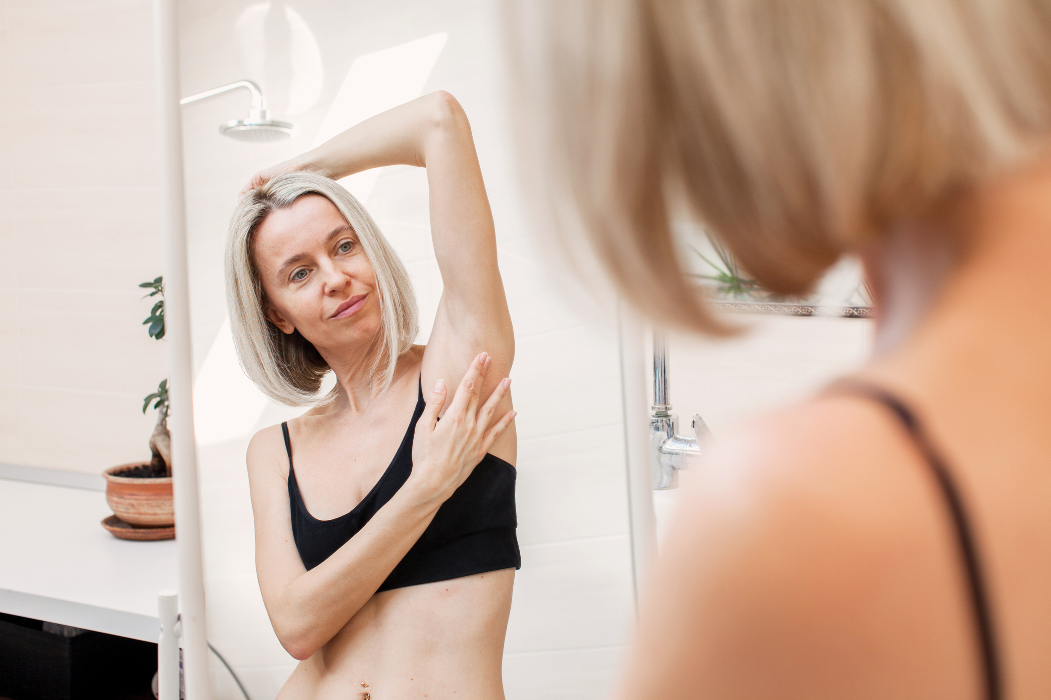 mature woman looking in mirror checking for signs of stage 0 breast cancer