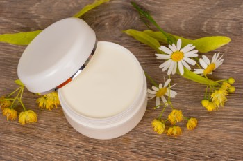 Arnica cream with flowers on a wooden table