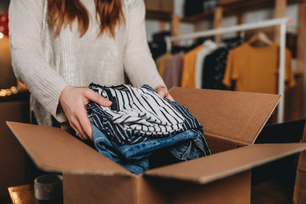 A millennial woman is preparing the shipment of some of her clothes.  