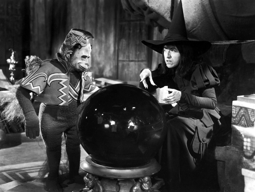 Margaret Hamilton and a winged monkey look into a crystal ball in a still from the film, 'The Wizard of Oz,' directed by Victor Fleming, 1939.