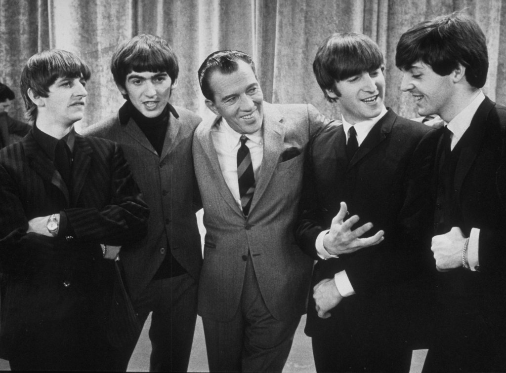 Television host Ed Sullivan (center) smiles as he stands, with the members of British rock group The Beatles, on the set of his television variety series, 'The Ed Sullivan Show' at CBS's Studio 50, New York, New York, February 9, 1964. Pictured are, from left, Ringo Starr, George Harrison, Sullivan, John Lennon, and Paul McCartney. The photo was taken prior to the group's debut performance on the show later that day.