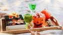 Halloween Romance Books: A wooden tray filled with green drinks, bowls of popcorn, candles, pumpkins and a book