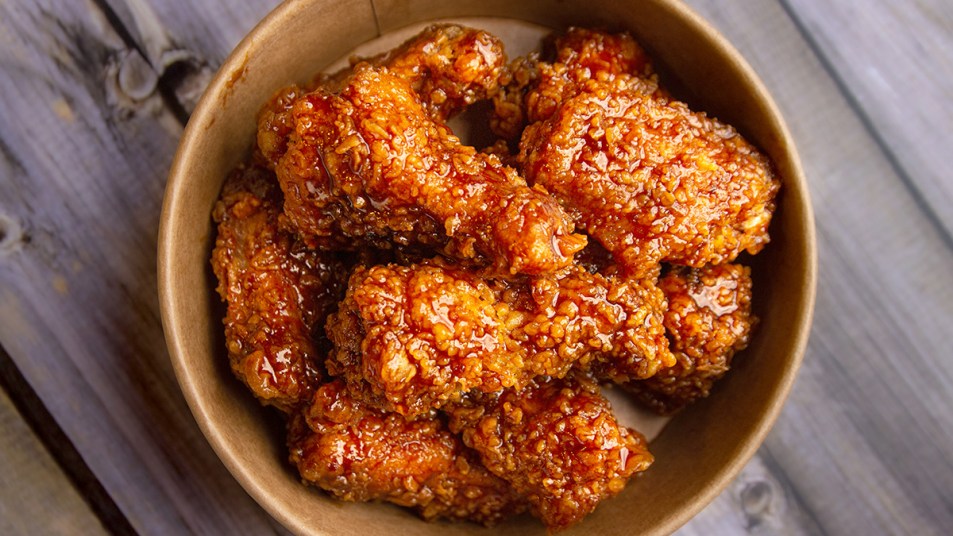 A bucket of fried chicken tossed in a hot honey sauce