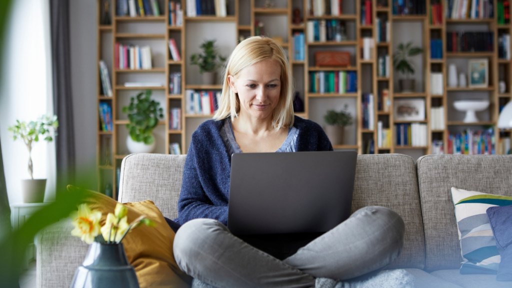 Woman at home sitting on couch using laptop .(weekend work from home jobs)