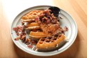 close up of sliced bacon waffles with fried chicken on plate