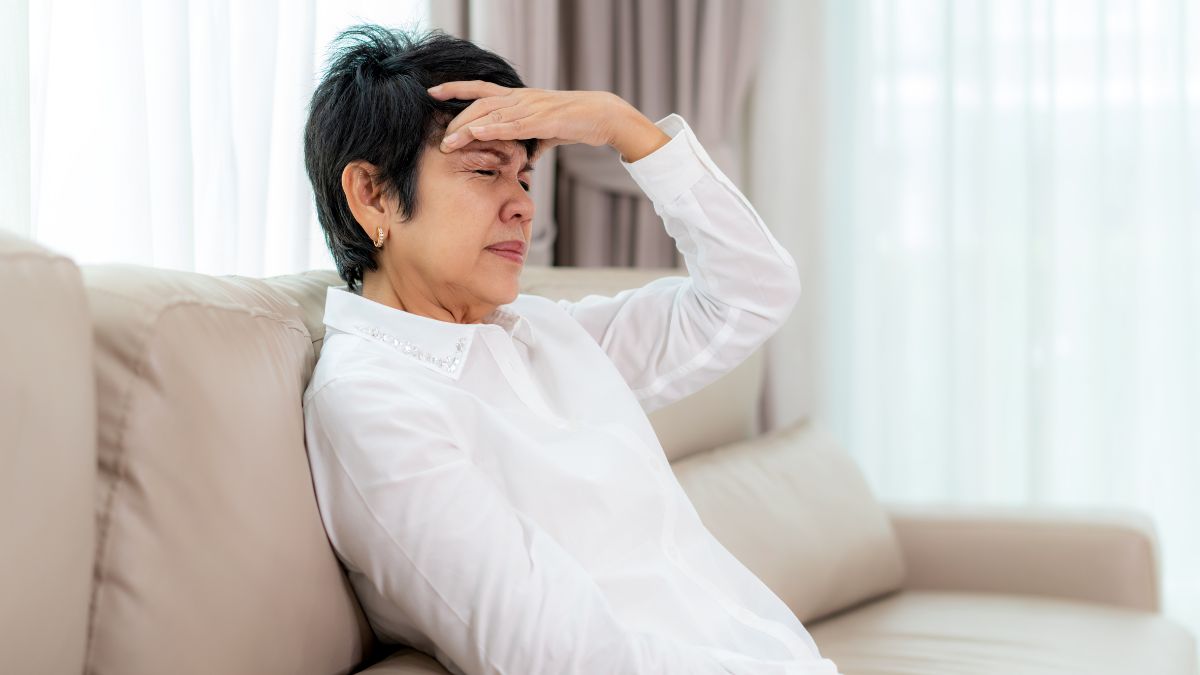woman witting on couch with a headache—concussion symptoms