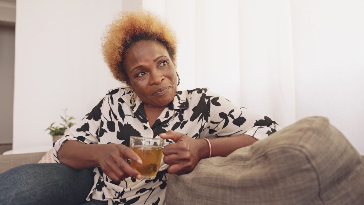 woman sitting of sofa drinking a cup of tea, which is a way to get healthy from your couch