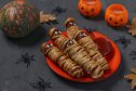 plate of halloween mummy hot dogs with candy eyes