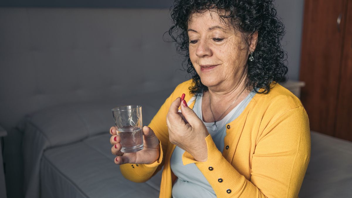 woman taking allergy pill with glass of water—how to relieve ear pressure