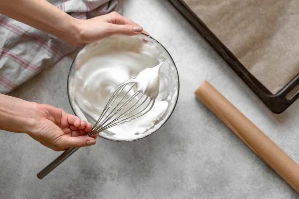 woman whipping meringue into stiff peaks for pavlova royale recipe