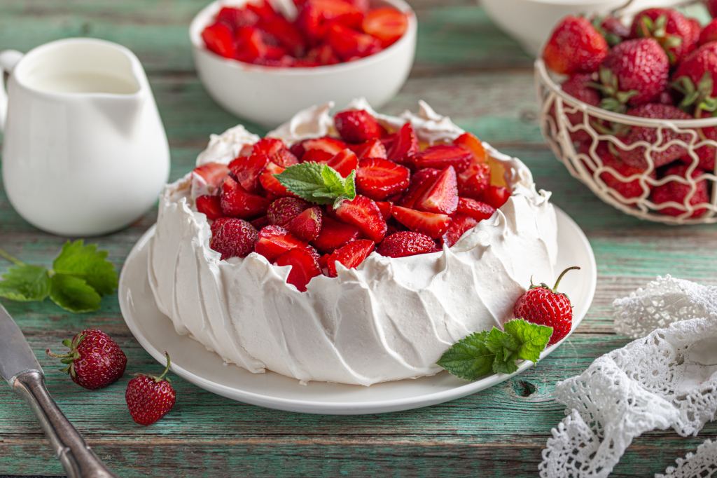 homemade strawberry pavlova cake on plate with fresh strawberries and mint