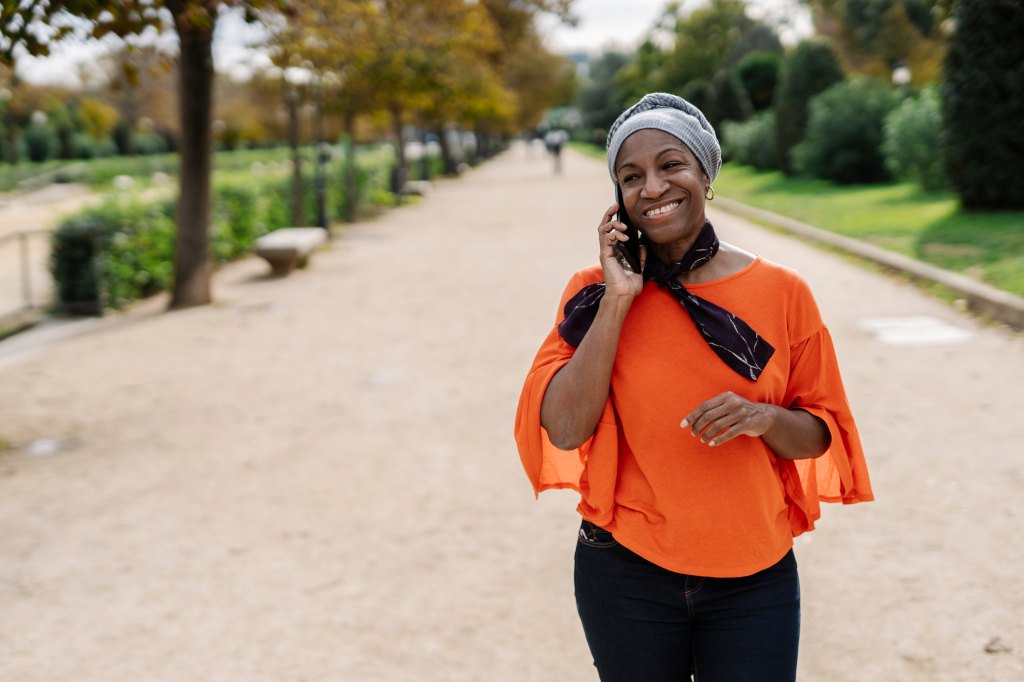 mature woman taking a work call outside for less sitting and reduced lower back pain