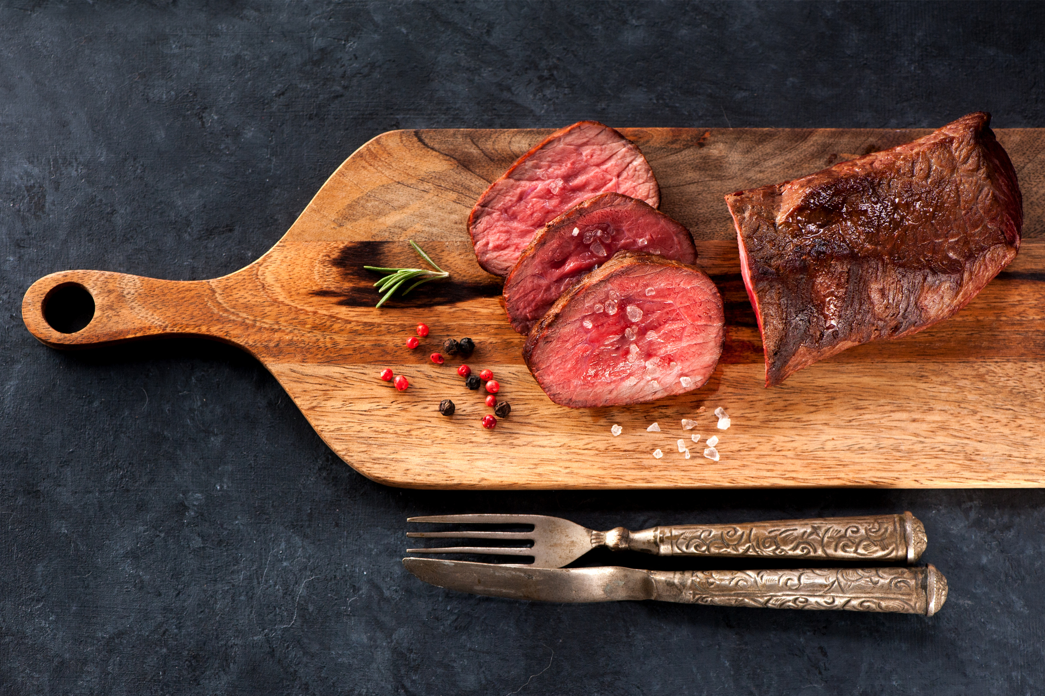 sliced roasted beef tenderloin on wooden cutting board