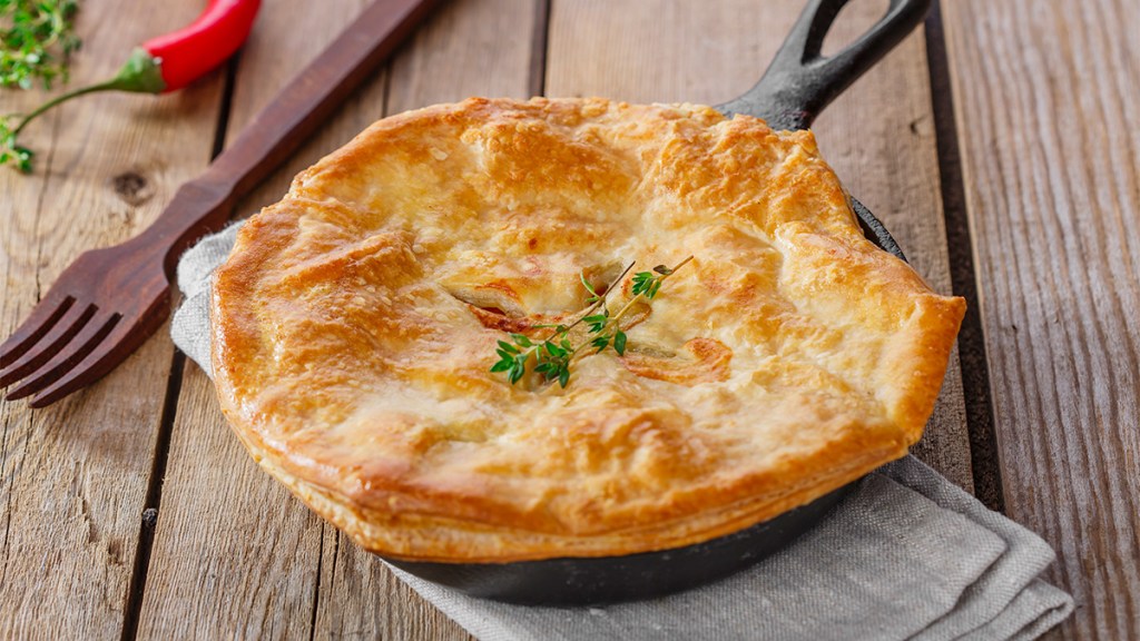 Chicken pot pie topped with puff pastry in a cast iron skillet