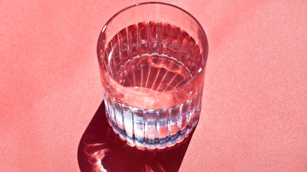A glass of water on a pink background