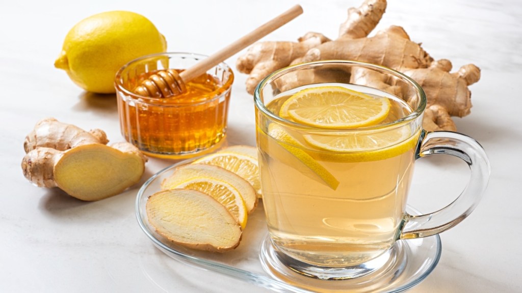 A clear glass of ginger tea with lemon slices and fresh ginger, which starts to ease gout pain in 10 minutes