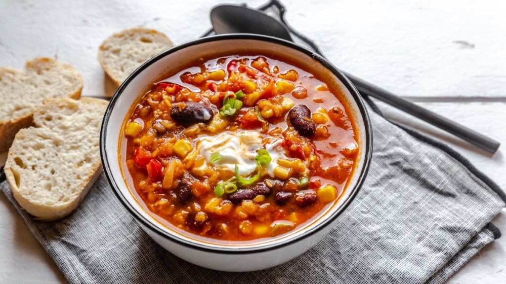 A bowl of vegetable chili with bread, which can reduce osteoporosis risk for those who don't want to take drugs