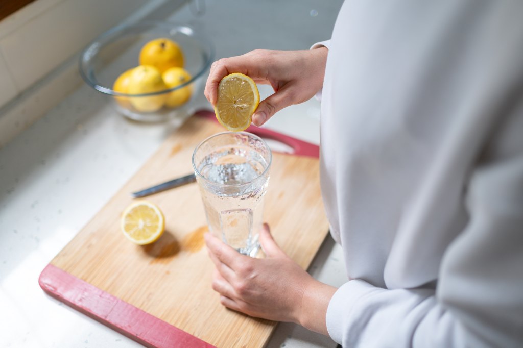 squeezing lemon juice into glass of water