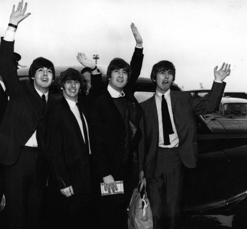 August 18, 1964: The Beatles wave to fans at London Airport. 