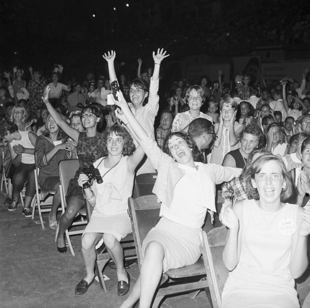 Young Beatle fans scream, wave, and cheer with excitement at the convention hall in Atlantic City, New Jersey.