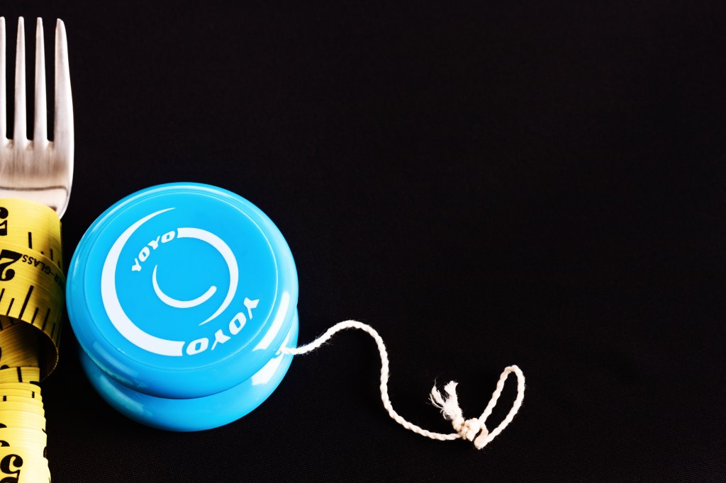 yo yo next to fork with measuring tape wrapped around it representing fluctuating weight