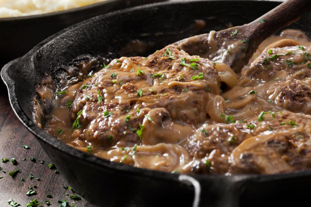 cooking Salisbury steak in cast iron skillet with mushroom gravy sauce