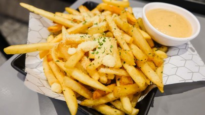 Plate of crab fries seasoned with Old Bay and served with cheese sauce for dipping