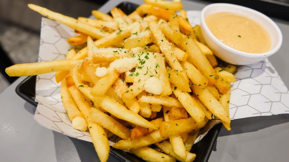 Plate of crab fries seasoned with Old Bay and served with cheese sauce for dipping