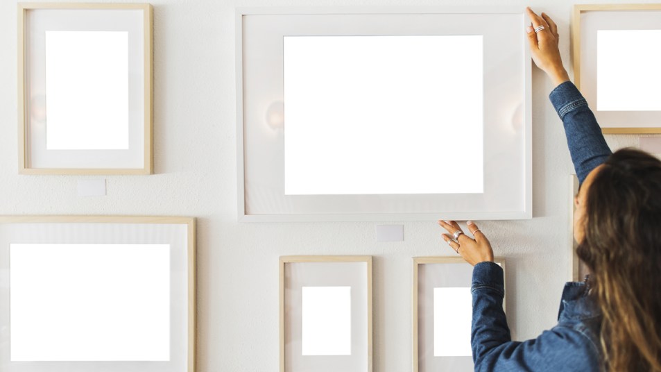 woman hanging frames on the wall