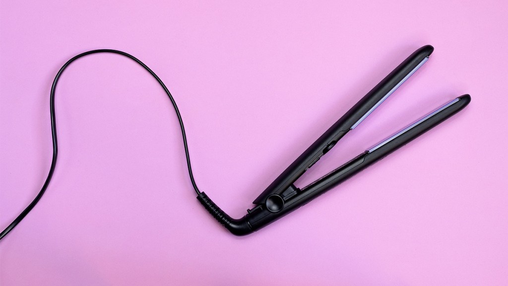 A straightening iron for hair on a pink backdrop
