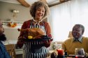 mature woman bringing a frozen cooked turkey to last-minute thanksgiving feast