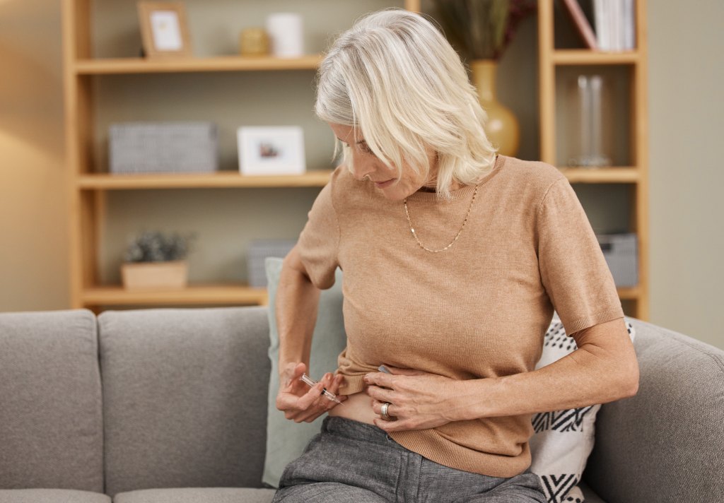 woman injecting herself with insulin on the sofa at home