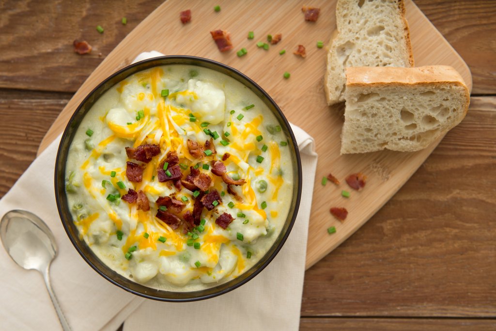 crockpot potato soup by Paula Deen in bowl with slice of bread on cutting board