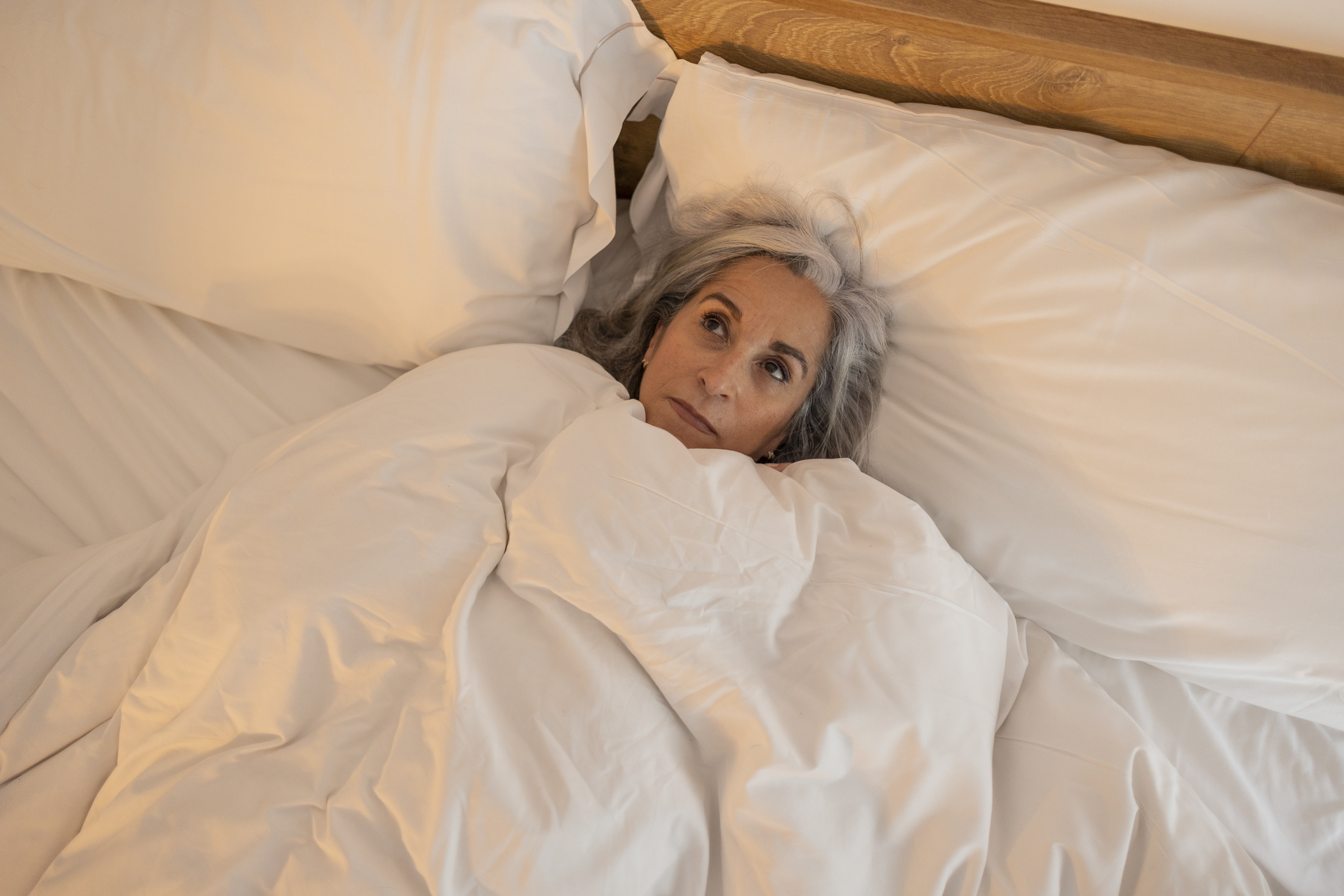 senior woman in bed can't sleep, pensive with insomnia