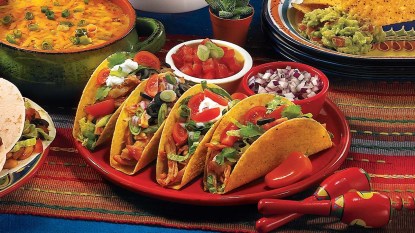 Table with plates of Tex Mex food included crunchy and soft tacos made with recipes perfect for Taco Tuesday
