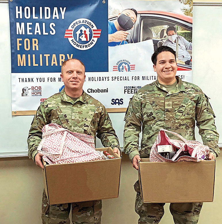 Two Servicemen holding Holiday Meals for Military Families kits