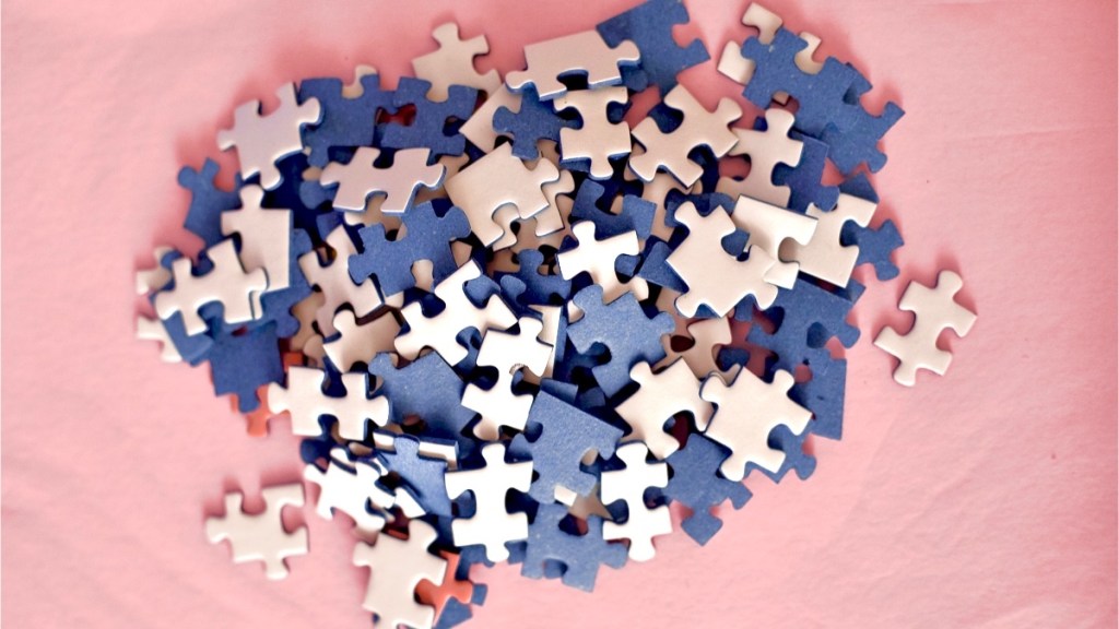 Blue and white jigsaw puzzle pieces on a pink background