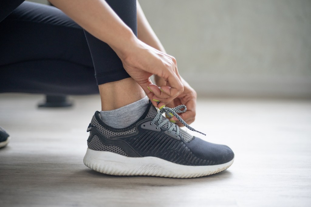 Woman tying running shoes to prevent calluses
