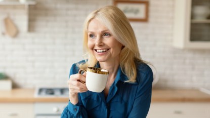 A blonde woman in a blue shirt drinking tea as one of 7 natural menopause treatments that work