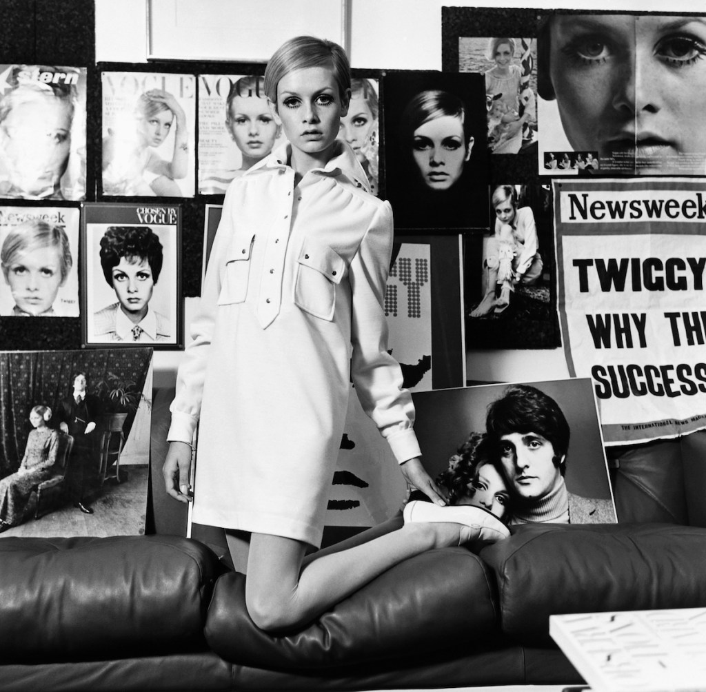 The British actress and model Twiggy, models a shirt dress amidst posters of her previous work, 1967