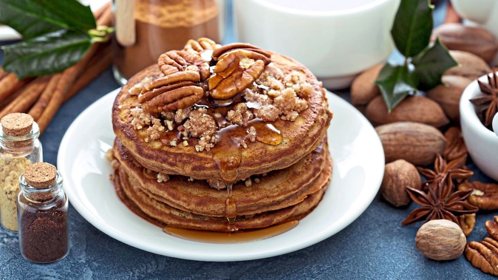 Pancakes topped with maple syrup and pecans