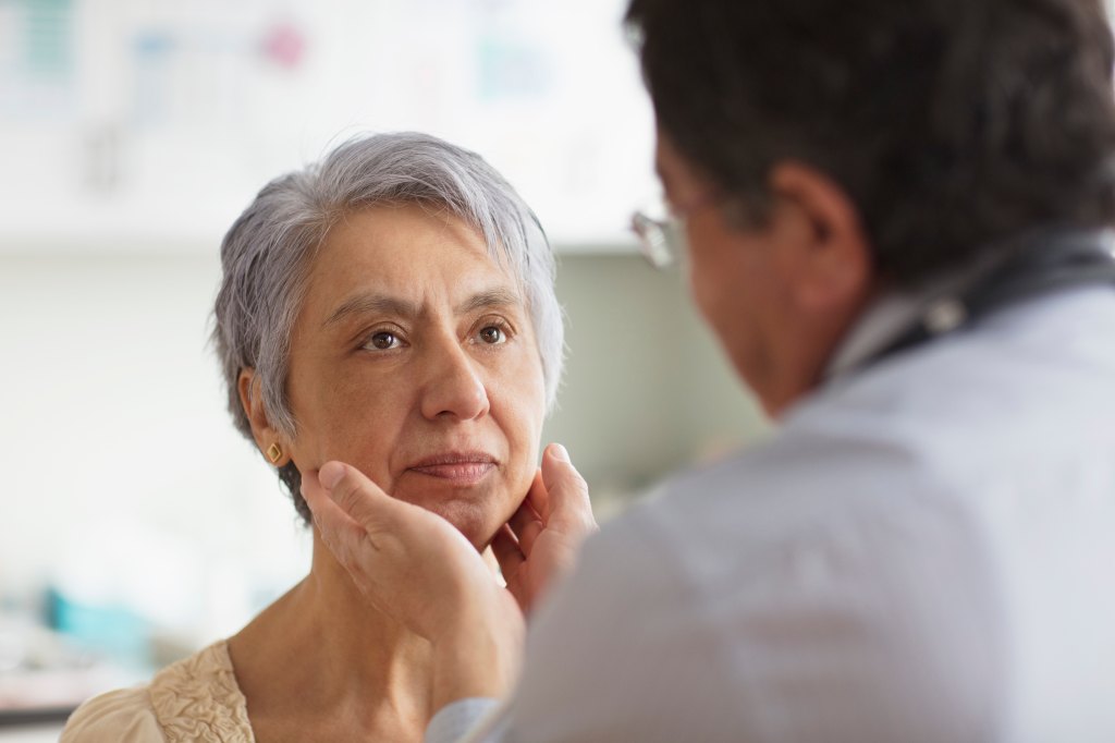 doctor examining woman's face and neck
