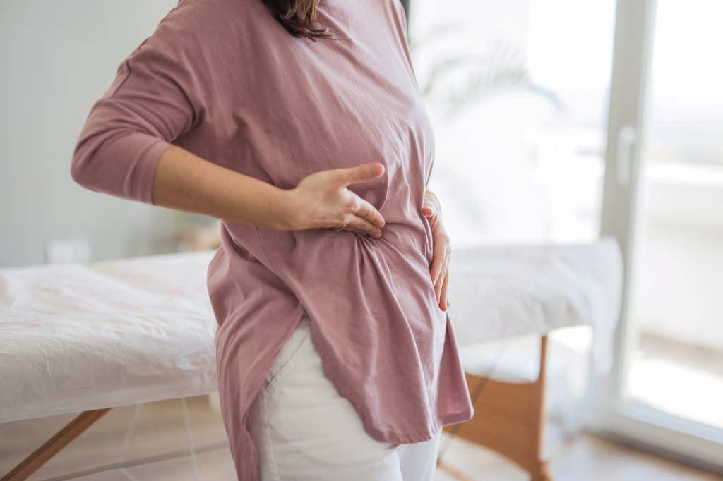 Woman points on the ribcage to show where the pain is