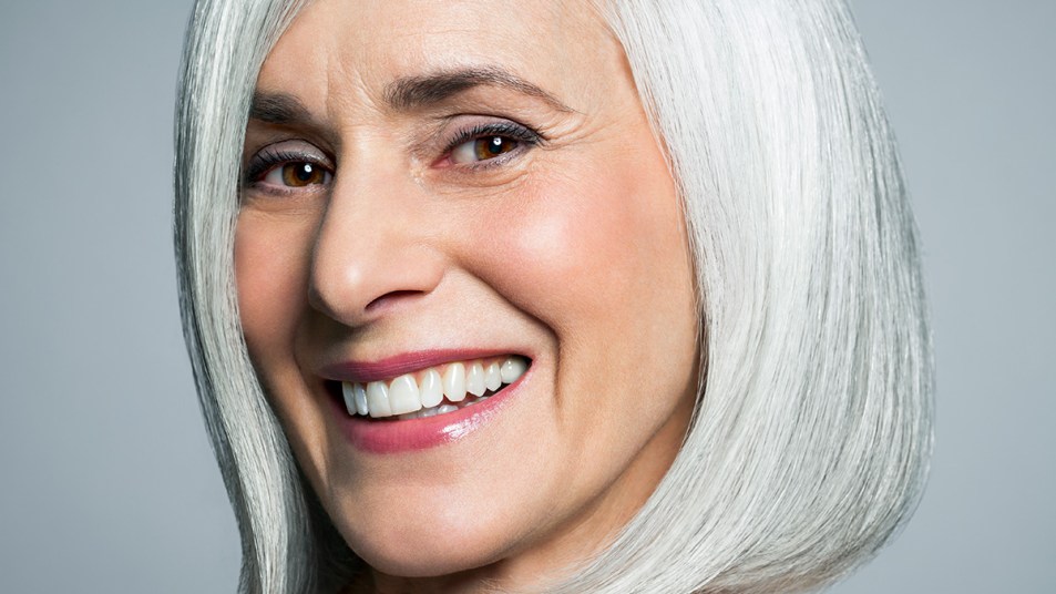 Woman with gray hair who is smiling and has a plump-looking pout after learning what a double lip line is and creating a similar effect